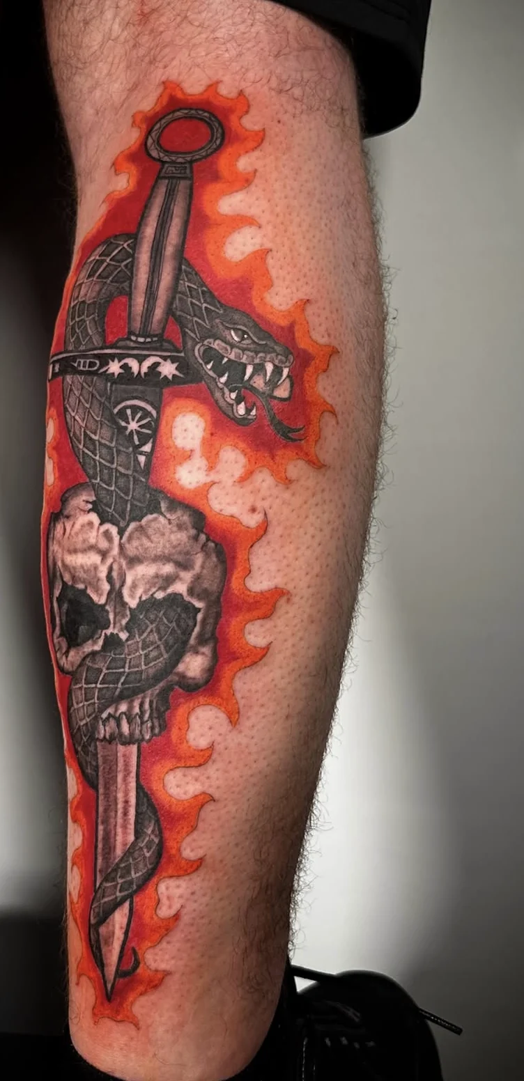 Custom skull and dagger calf tattoo with red flames by Suze Tattoos, London